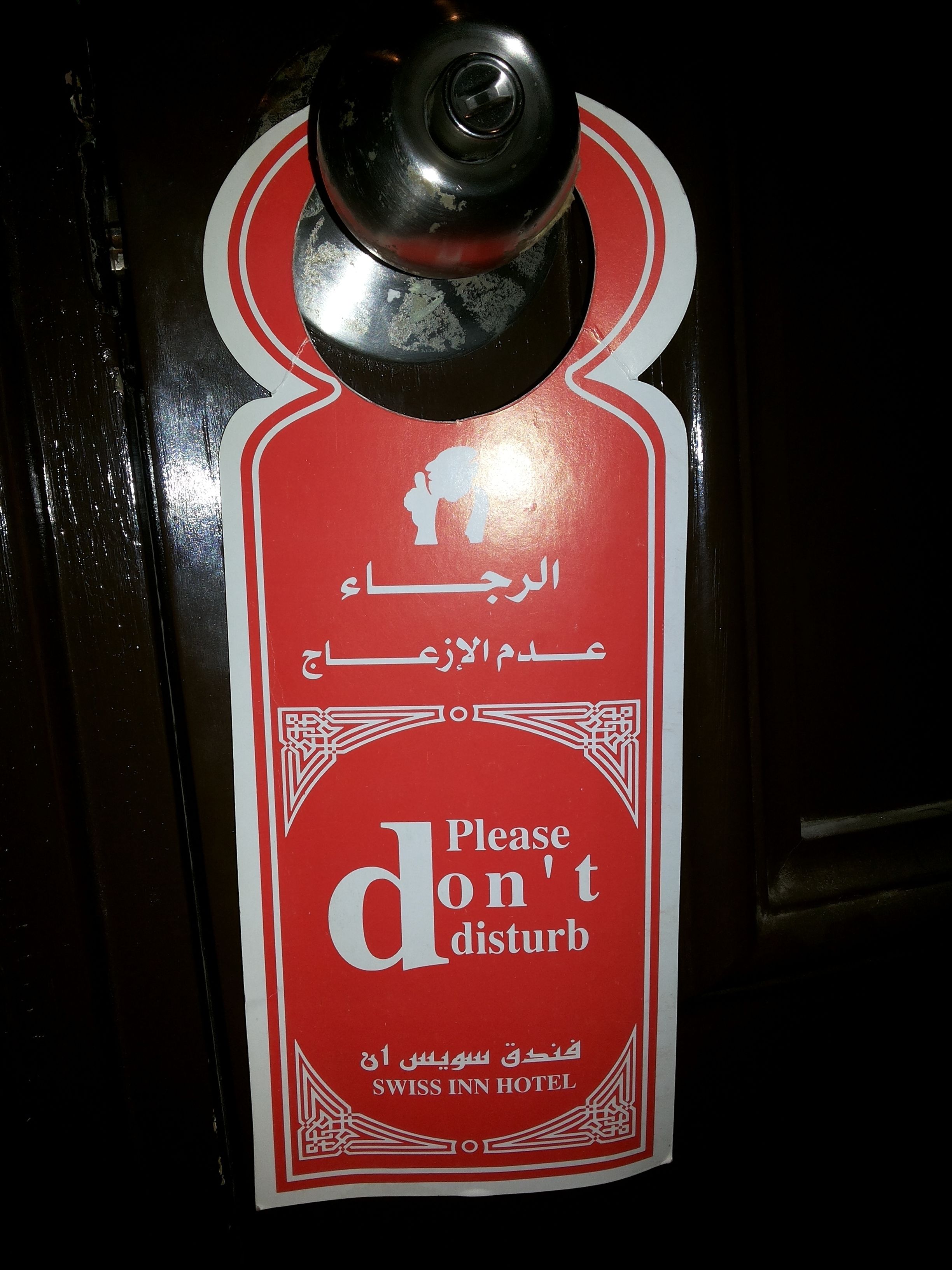 A door with a sign that reads "Please don't disturb" and "SWISS INN HOTEL" in multiple languages.