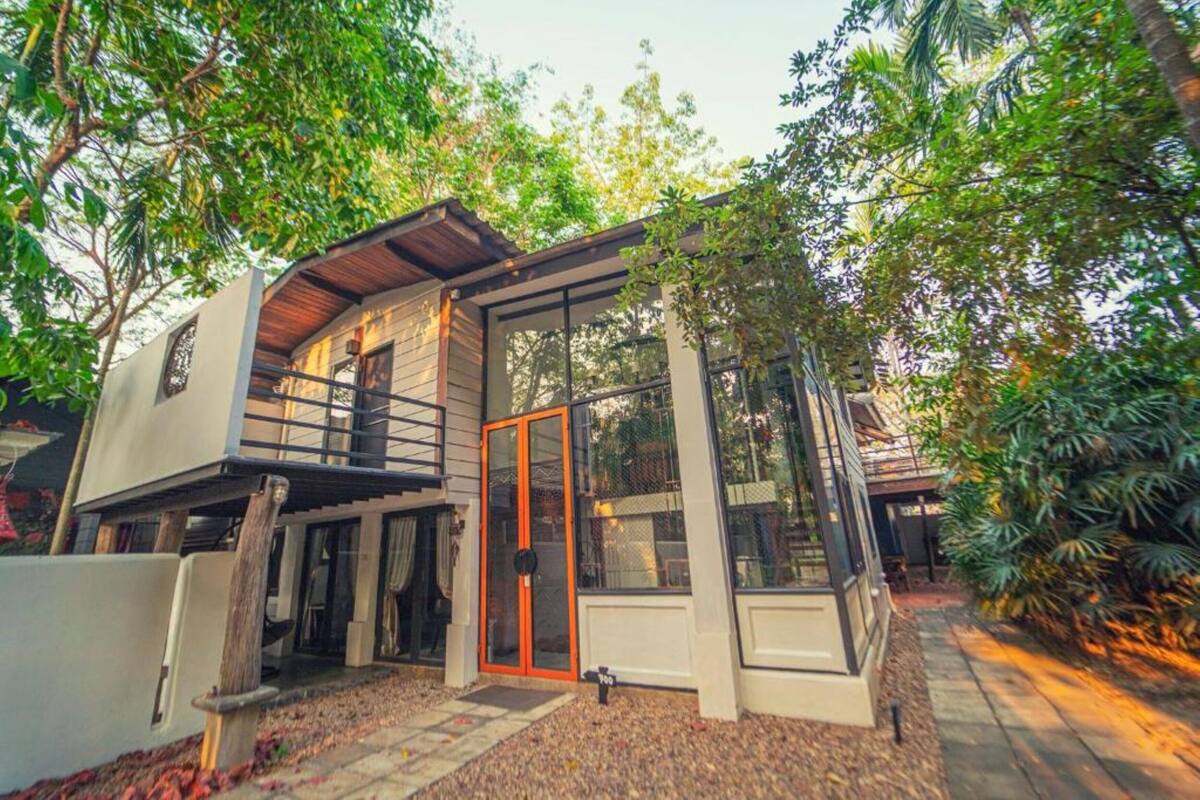 Una casa moderna con un porche cubierto, ventanas amplias y una terraza de madera.