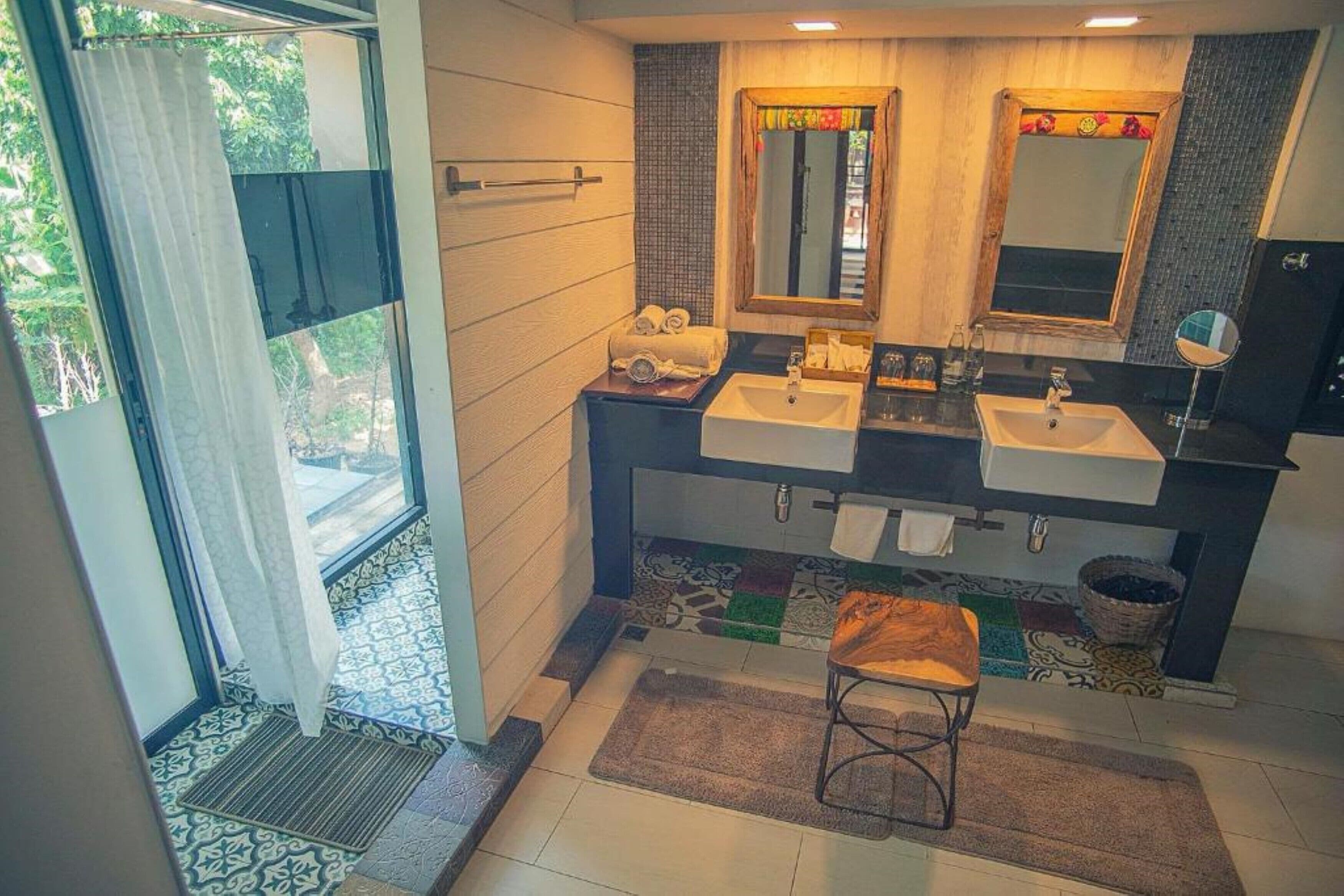 A bathroom with two sinks, a large mirror, and a window with curtains.