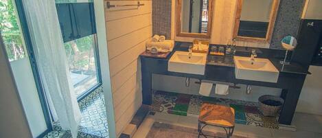 A bathroom with two sinks, a large mirror, and a window with curtains.