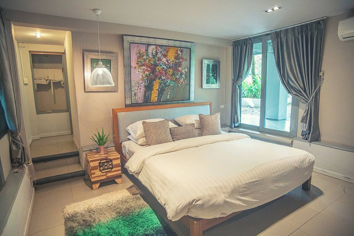 Un dormitorio con una cama grande, un cuadro en la pared y una ventana con cortinas.