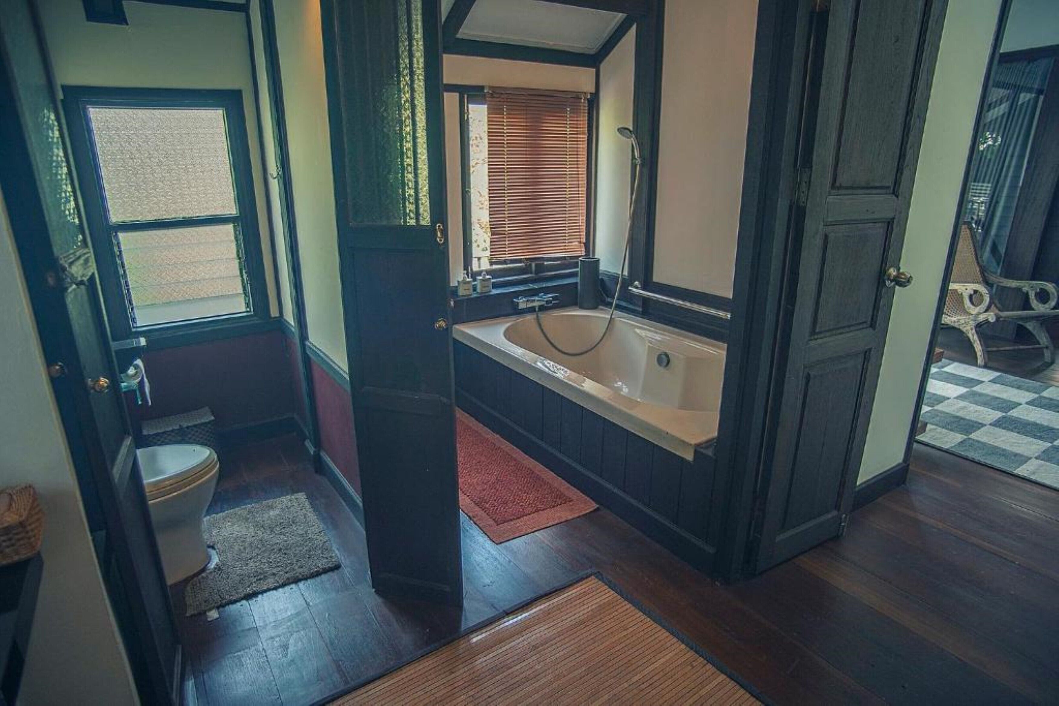 A bathroom with a bathtub, toilet, and window.