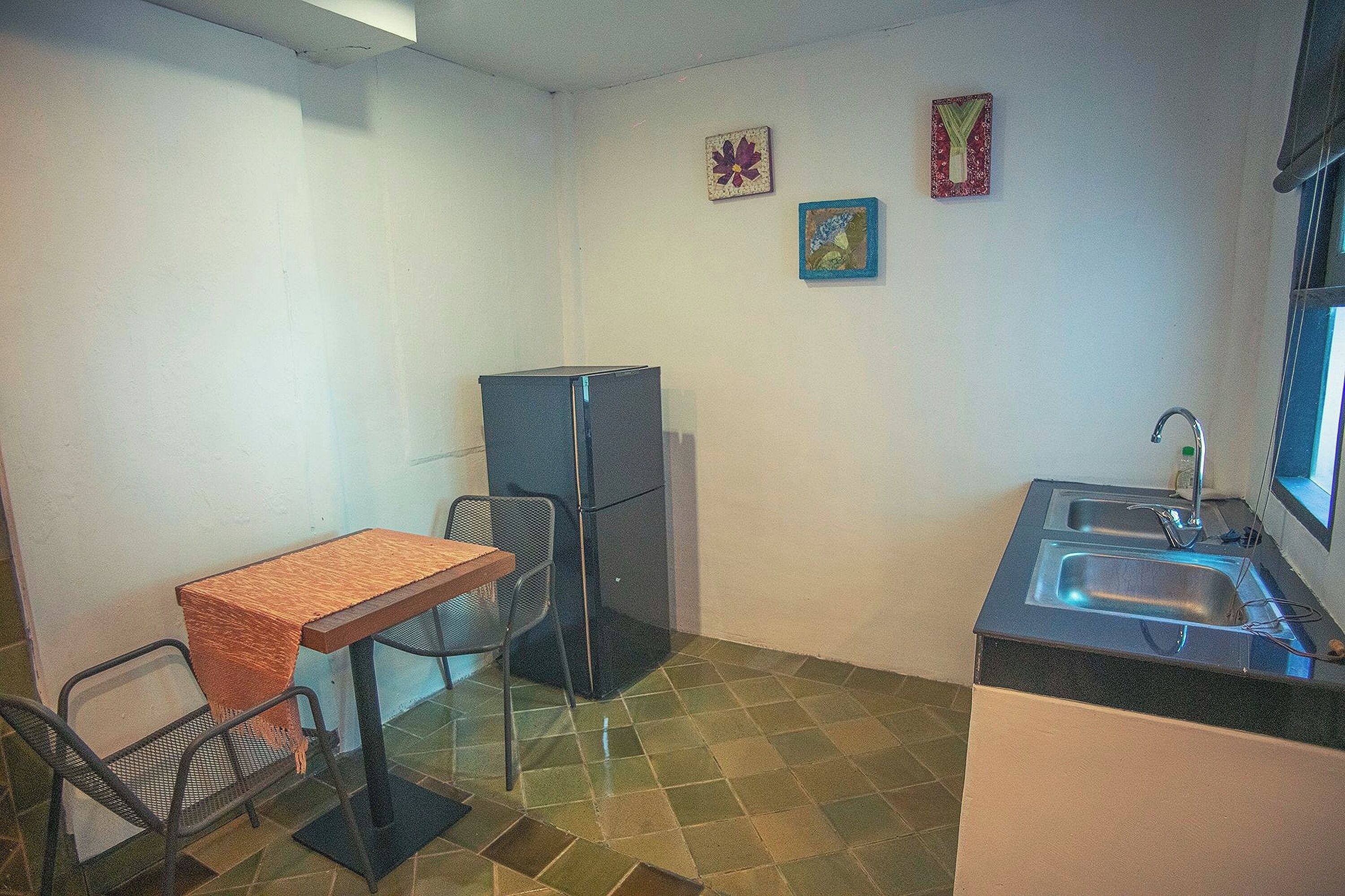 A compact kitchen with a dining table, chairs, a refrigerator, and a sink.