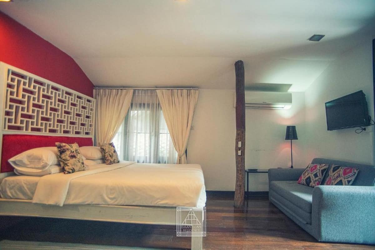 Una habitación de hotel con cama, sofá, televisión y un panel decorativo en la pared.