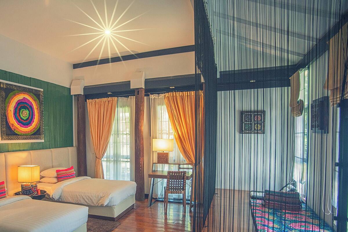 Habitación de hotel con dos camas, una obra de arte colorida en la pared, un escritorio con una silla y vistas a través de una cortina.