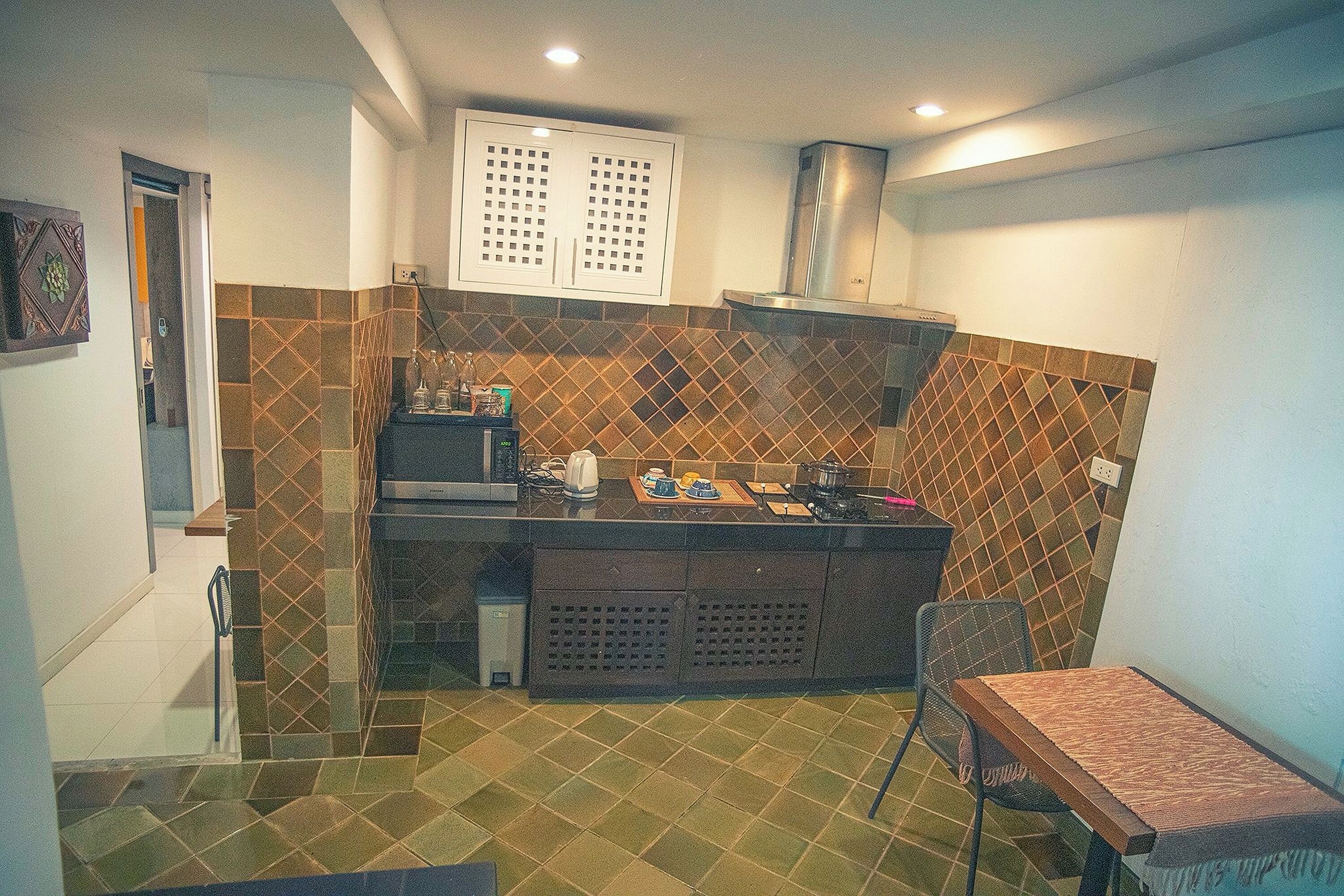 A compact kitchen with a tiled backsplash, a built-in stove, and a small dining area with a table and chair.