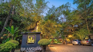 Señal de Baansuan Residence en una zona verde y arbolada, con caminos empedrados y coches aparcados.