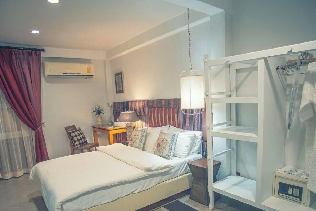 Un dormitorio con cama, mesita de noche con lámpara, armario y equipo de aire acondicionado.