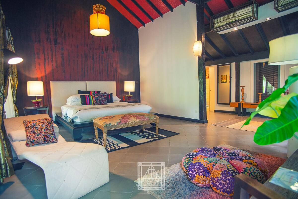 Un dormitorio espacioso con una cama grande, una zona de estar con un banco y un comedor.