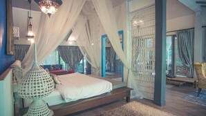 Un dormitorio con cama, una silla colgante y una lámpara decorativa.