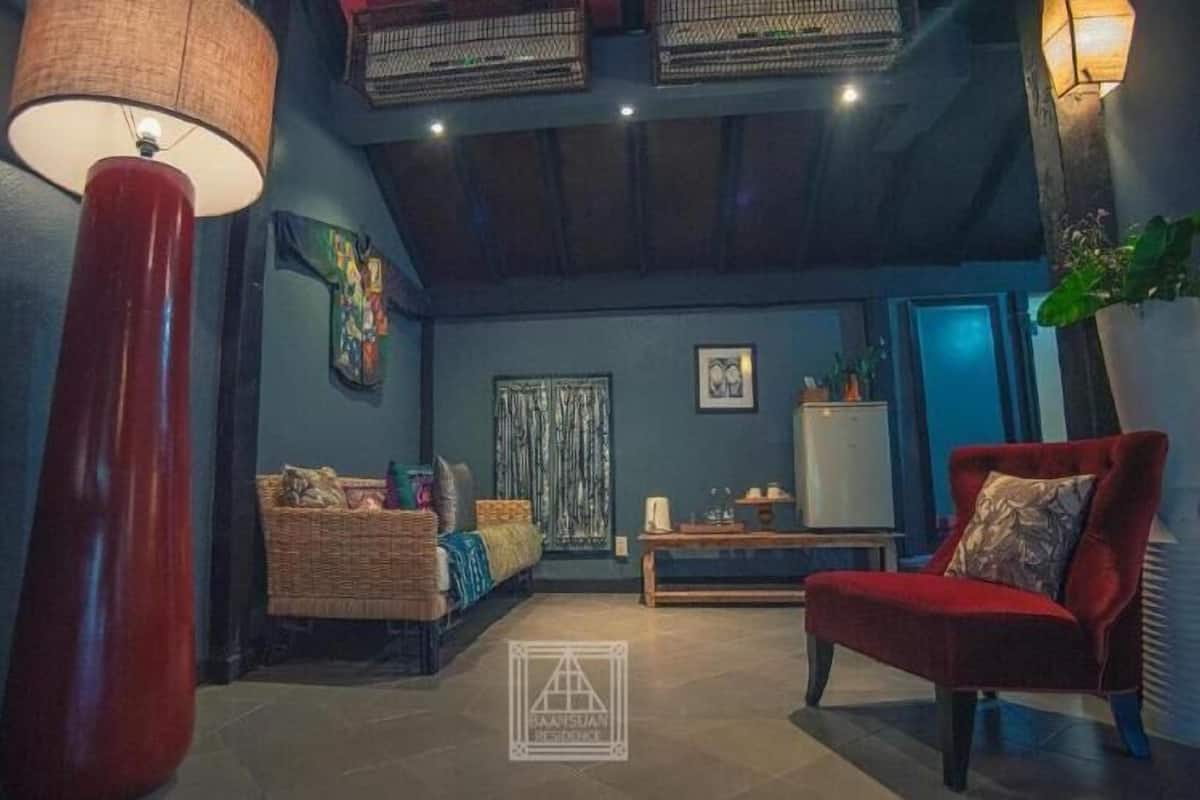 Una sala de estar acogedora con un sillón rojo, un sofá, una lámpara y un adorno en la pared.