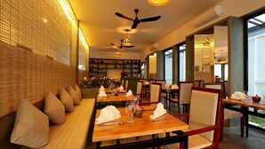 Restaurante com mesas de madeira, bancos acolchoados e um ventilador de teto.