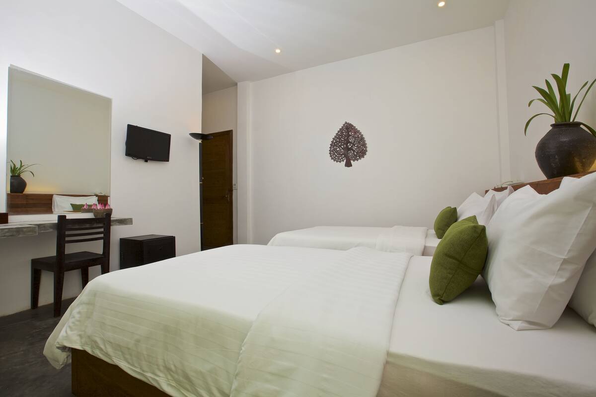 Ein Hotelzimmer mit Bett, Schreibtisch, Stuhl und Fernseher an der Wand.