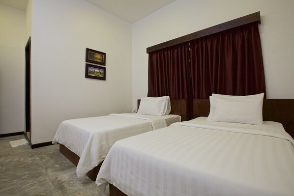 A hotel room with two single beds, a wooden headboard, a dark red curtain, and two framed pictures on the wall. - De Sonyn Boutique (Siem Reap)