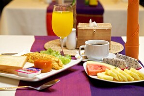 Een ontbijttafel met toast, omelet, fruit en een glas sinaasappelsap.