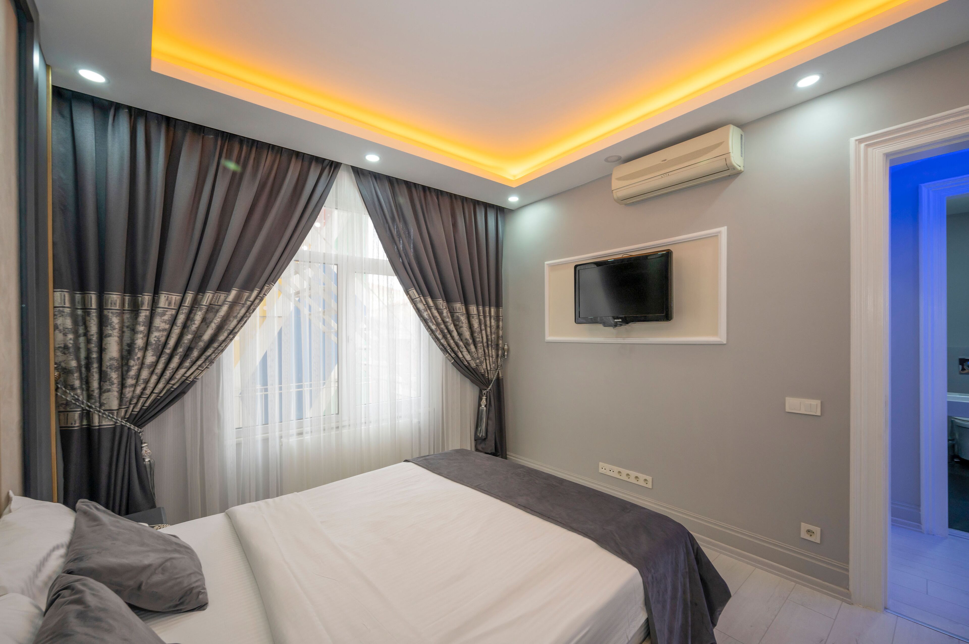 Ein Hotelzimmer mit Bett, Vorhängen, Fernseher und Klimaanlage.
