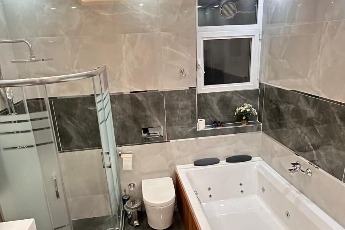 Un baño moderno con una bañera grande, cabina de ducha y un inodoro.