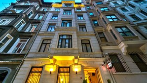 A multi-story building with a classic architectural style, featuring numerous windows and a prominent entrance with illuminated signage. - Hotel Next2 (Istanbul)