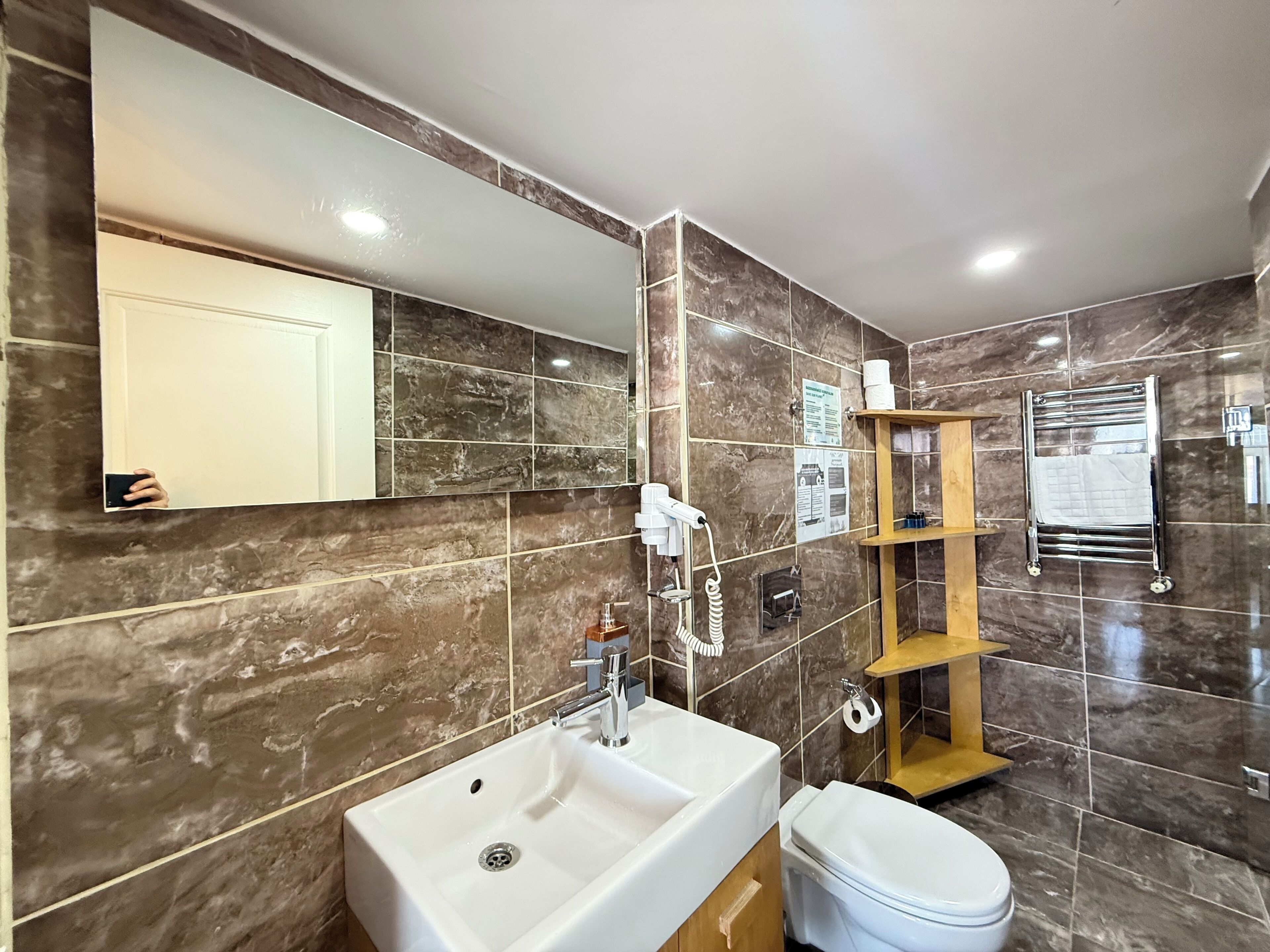 A bathroom with a white sink, a toilet, a mirror, and a towel rack.