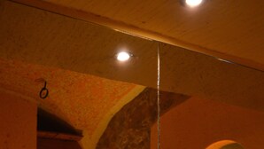 A room with a stone wall, wooden furniture, and a mirror reflecting the room's interior. - Hotel Wanda (Pinzolo)