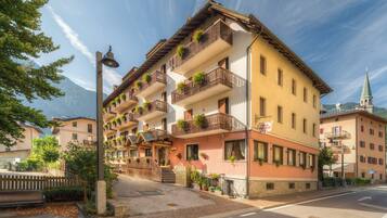 Experience the charm of traditional Alpine architecture at this hotel, featuring a symmetrical facade with balconies and a welcoming entrance.