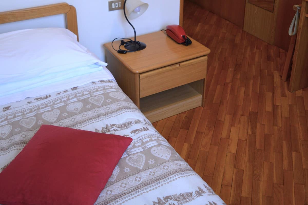 A bedroom with a bed, a nightstand, a lamp, and a telephone.