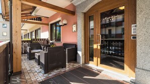 An outdoor seating area with wicker furniture and a tiled floor. - Hotel Wanda (Pinzolo)