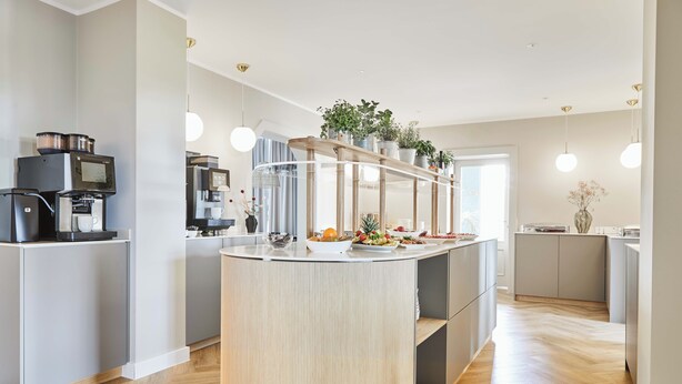 Una cocina moderna con una isla central, electrodomésticos integrados y suelo de madera.