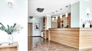 Una zona de recepción moderna con un mostrador de madera, suelo de mármol e iluminación colgante.