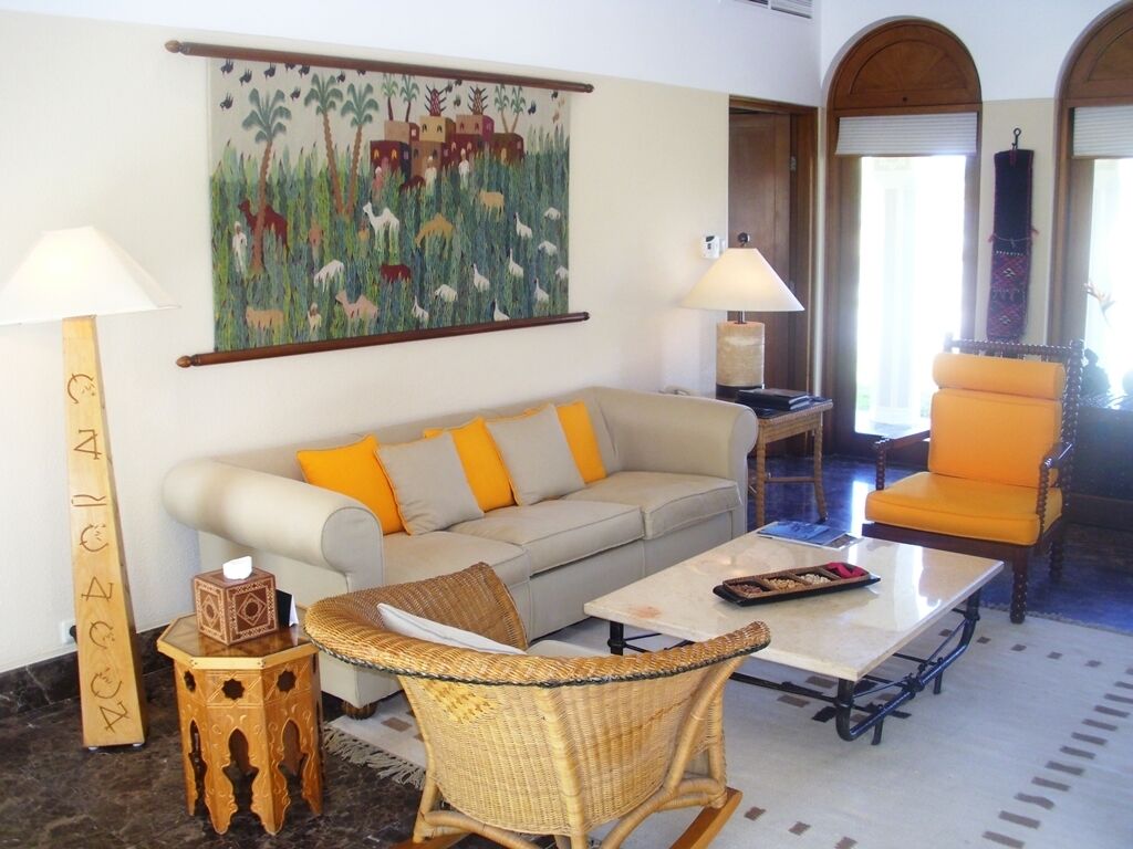Uma sala de estar com sofá, poltronas, mesa de centro e um quadro na parede.