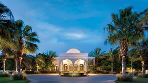 A hotel entrance with a fountain, palm trees, and a dome-shaped building. - The Oberoi, Sahl Hasheesh (Hurghada)