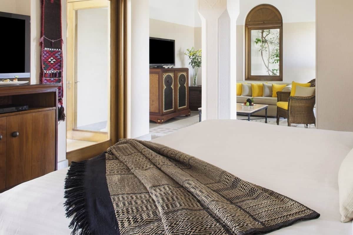 A hotel room with a bed, a television, a sofa, and a lamp.