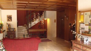 Un vaste espace de vie comprenant un escalier, un canapé rouge, un meuble en bois et un miroir décoratif.