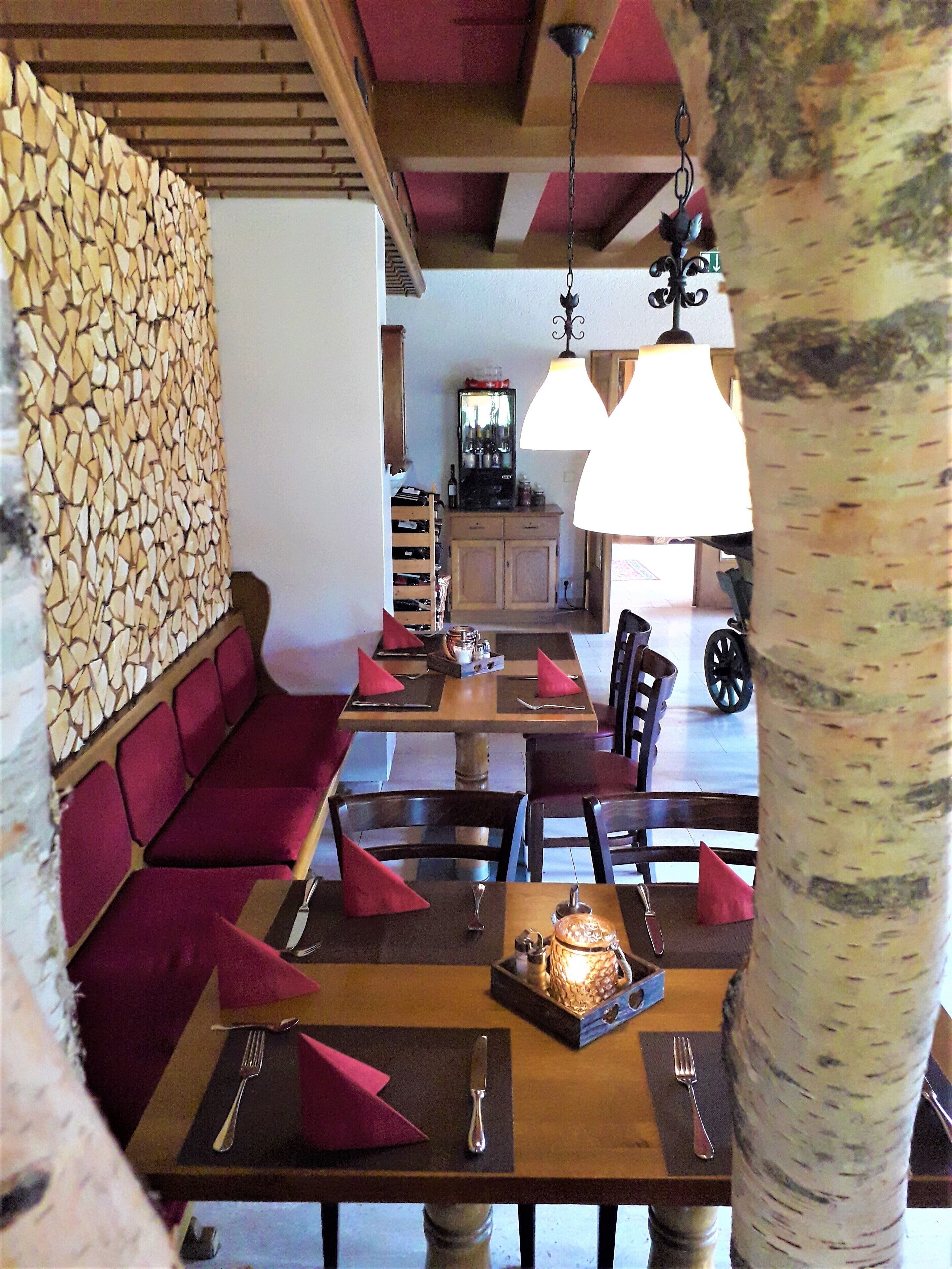 A dining area with a wooden table, red upholstered seating, and a stone wall.