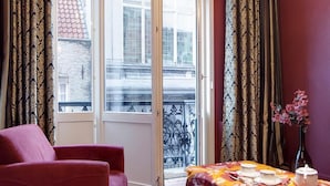 A room with a red sofa, a dining table with a yellow tablecloth, and a chandelier.