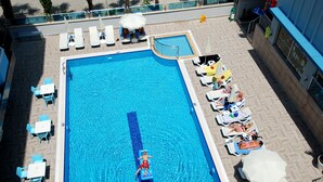 A swimming pool with lounge chairs and tables, a lifeguard chair, and a poolside area with a railing. - Kleopatra Ramira Hotel - All Inclusive (Alanya)