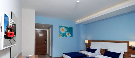 A hotel room with two beds, a desk, a TV, and a painting on the wall.