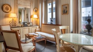 A cozy room with a sofa, chairs, a glass table, and a dresser with lamps. - Hotel de l'Avre (Paris)