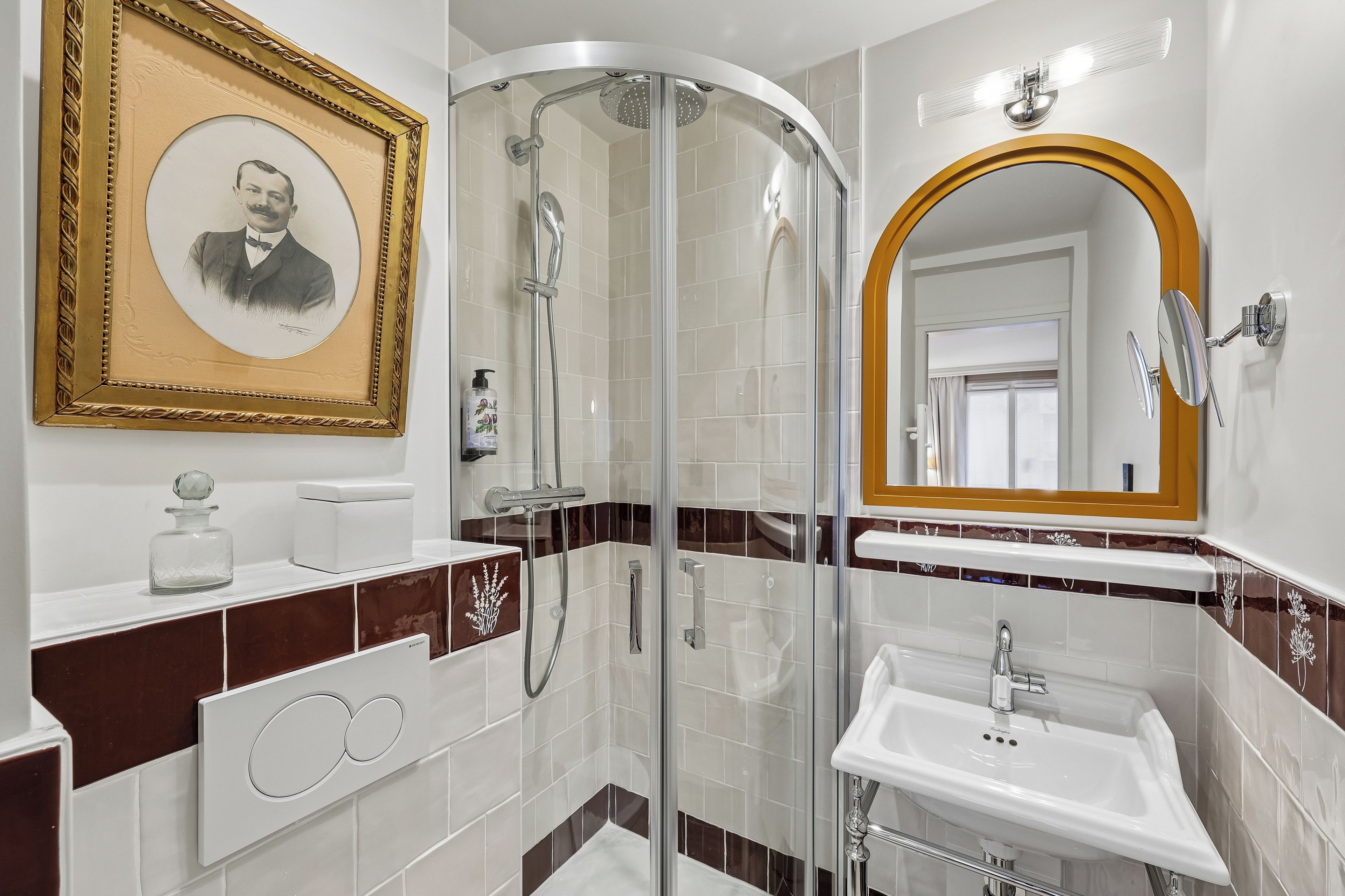 Un baño con cabina de ducha de vidrio, lavamanos blanco y espejo con marco de madera.