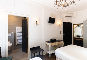 A hotel room with a bed, a desk, a television, and a bathroom visible through an open door. - Hotel de l'Avre (Paris)