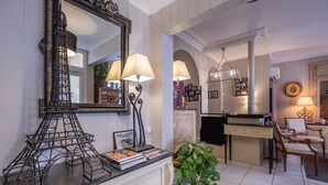 A well-lit room with a large mirror, a model of the Eiffel Tower, a desk with a lamp, and a potted plant. - Hotel de l'Avre (Paris)