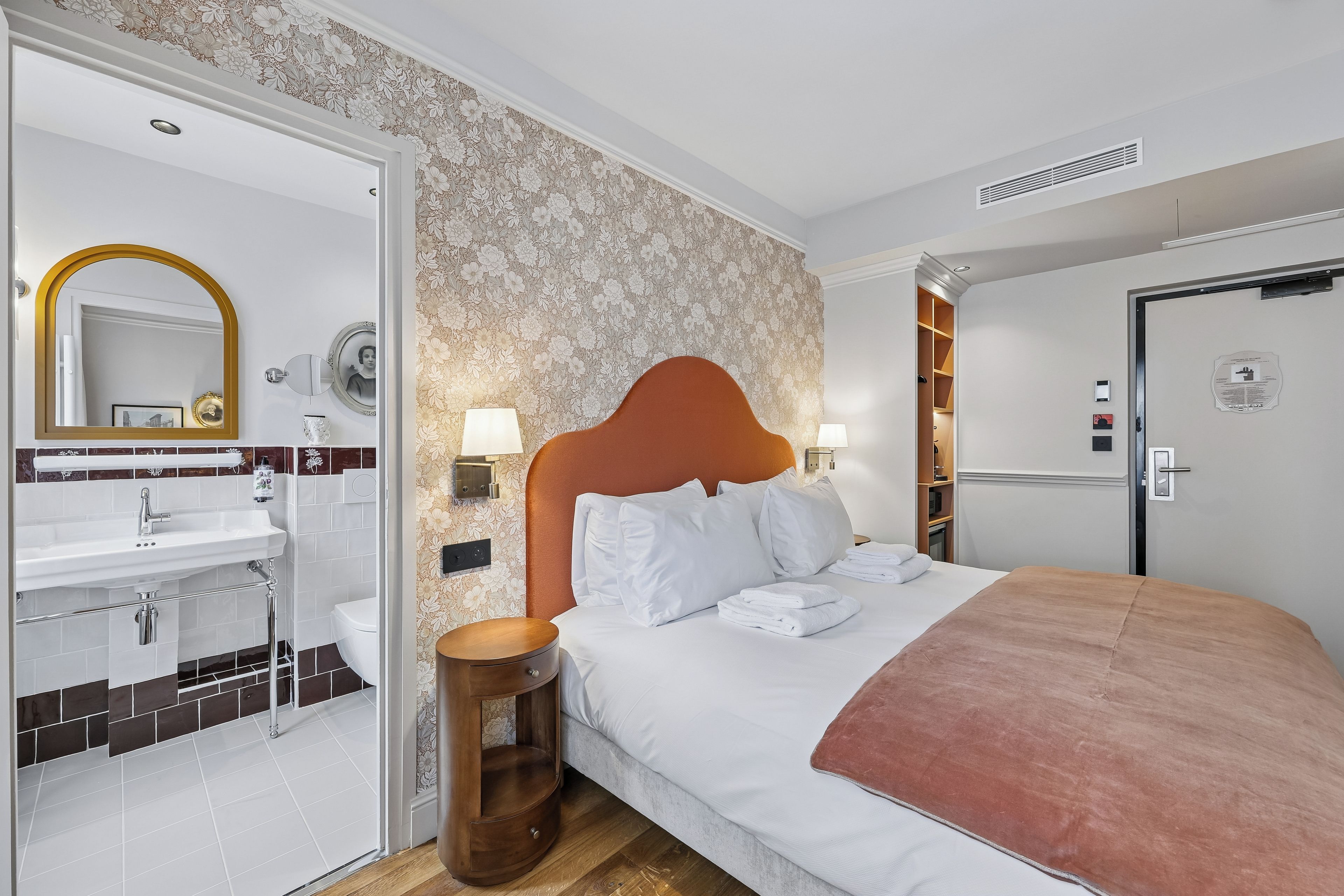 A hotel room with a bed, a bathroom, and a wardrobe.