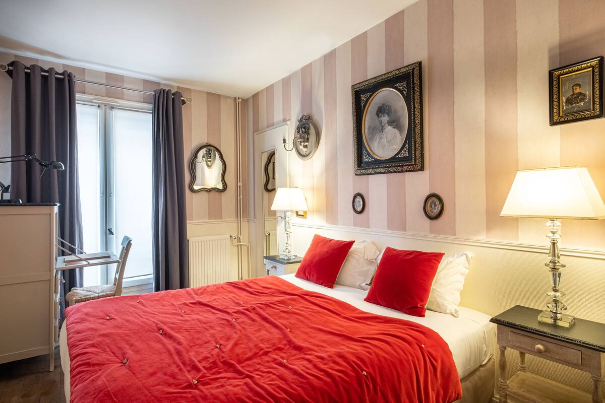 A hotel room with a bed, a desk, a chair, and a window with curtains.