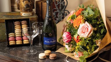 Une bouteille de champagne Nicolas Feuillatte, un verre de vin, des macarons et un bouquet de fleurs sur une table.
