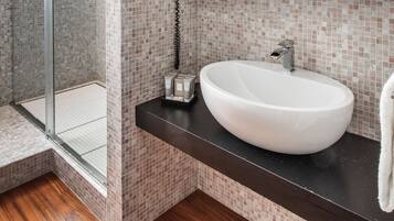 Un bagno con lavandino bianco, piano di lavoro scuro e pareti rivestite in piastrelle.
