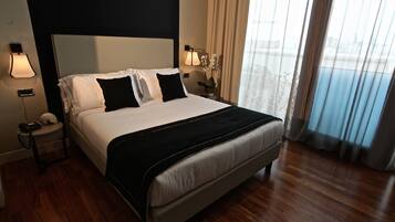 Une chambre d’hôtel avec un grand lit, une table de chevet avec une lampe et une vue sur l’extérieur par la fenêtre.