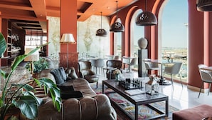 A spacious living area with a leather sofa, a coffee table, and a view of the city through large windows.
