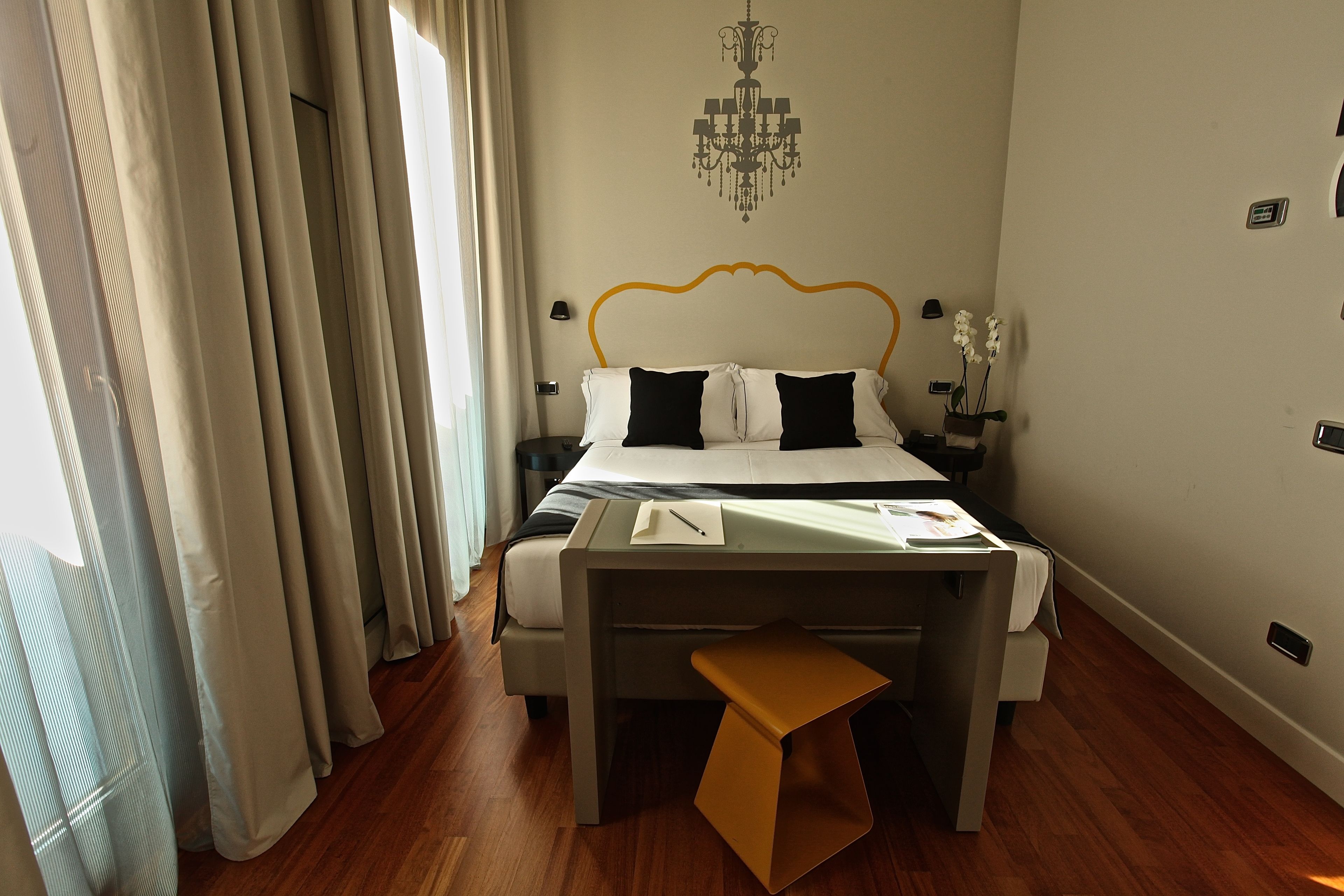 A modern hotel room with a bed, a desk, and a chair.