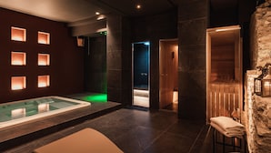 A spa room with a hot tub, a massage area, and a stone wall.