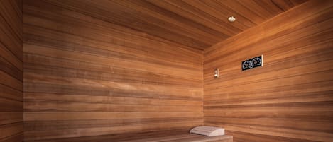 Una sauna con paredes y bancos de madera, un reloj y un cubo.
